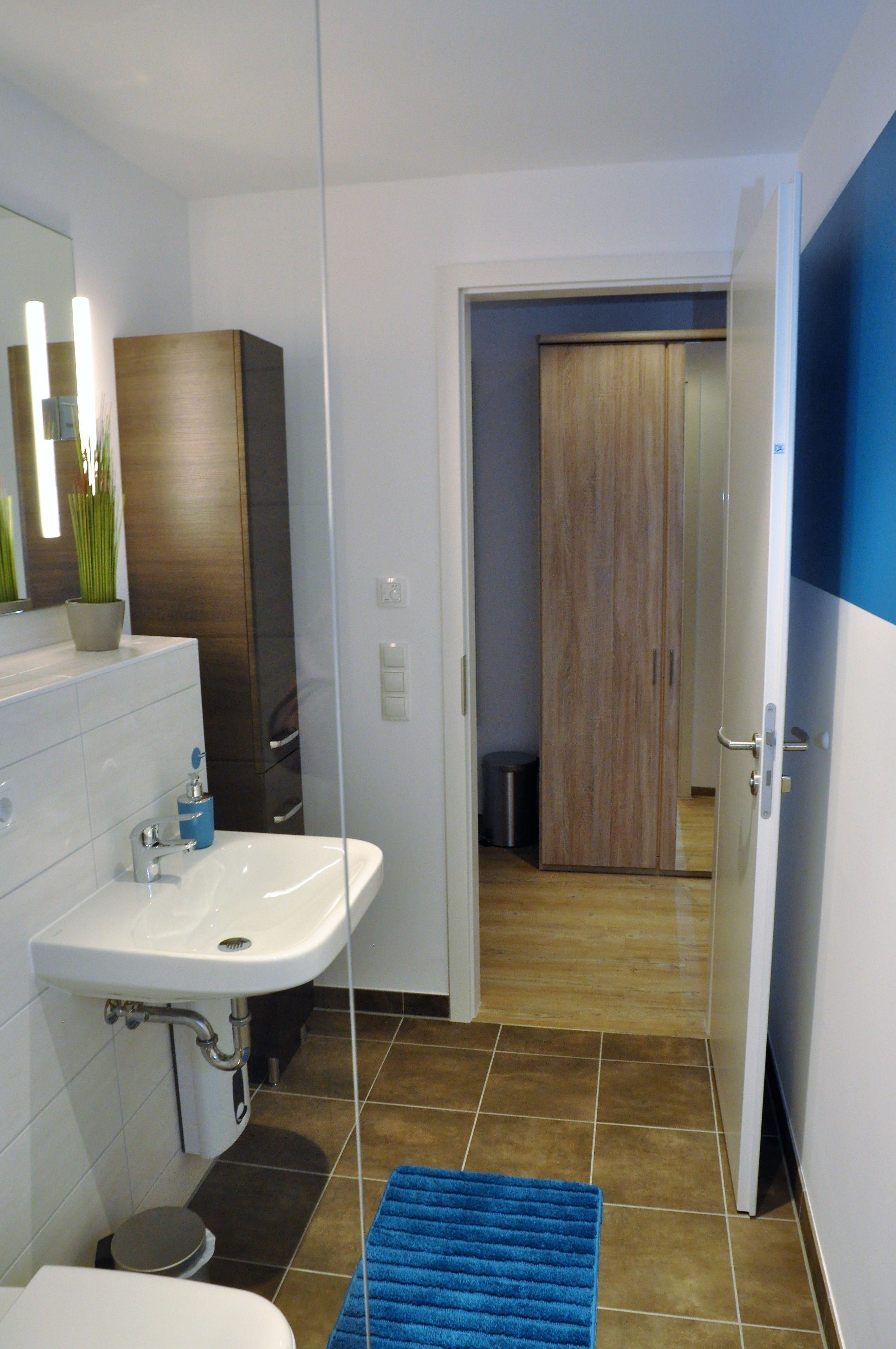 A modern bathroom with a white sink, mirror, and a blue rug.