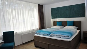 Una habitación de hotel moderna con una cama grande, un escritorio y una silla.