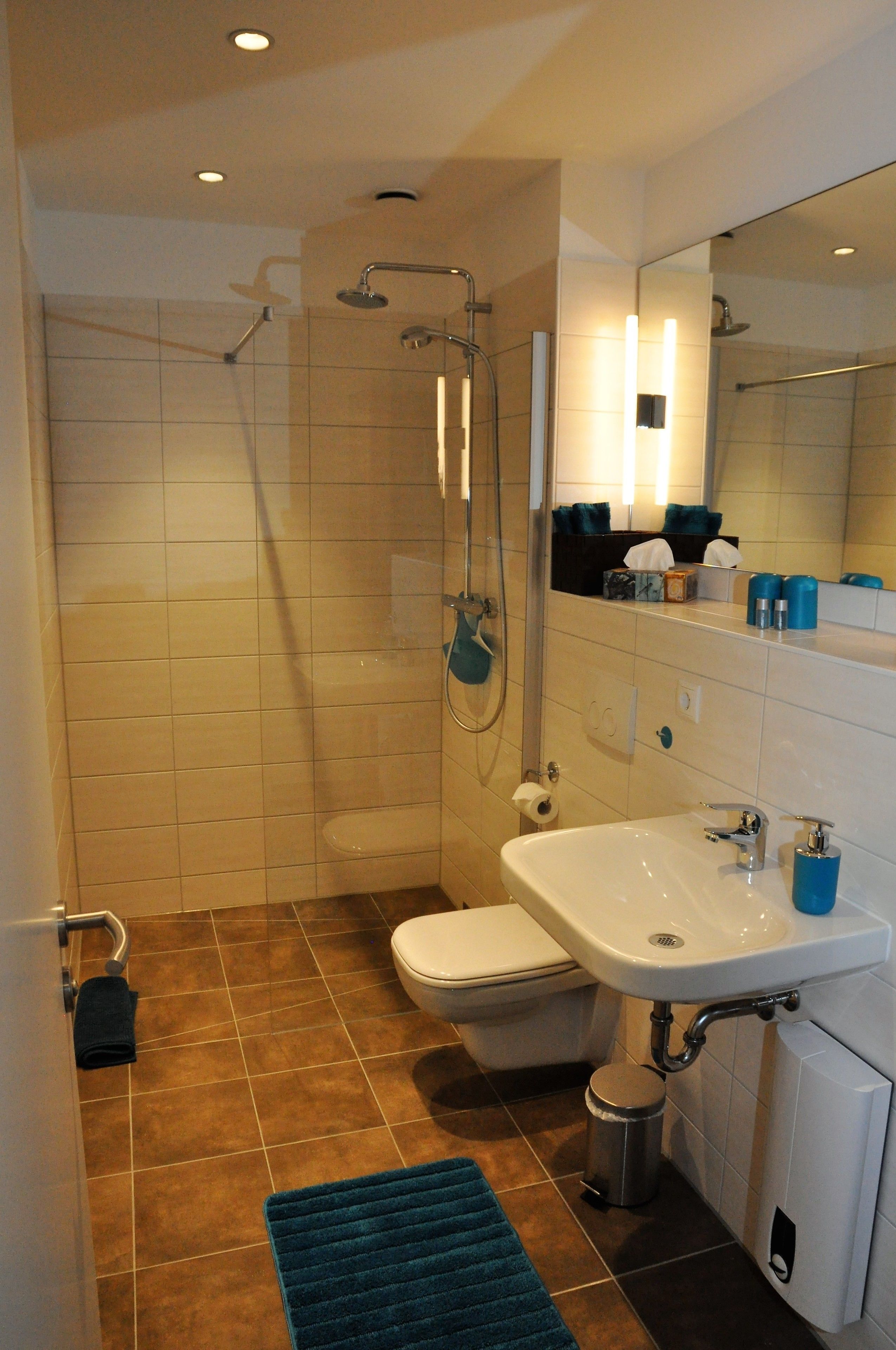 A modern bathroom with a shower, toilet, sink, and a mirror.