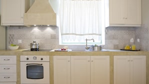 A kitchen with a built-in oven, a sink, and a window with a curtain. - Villa Kodria (Lefkada)