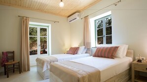 A bedroom with two beds, a wooden ceiling, and large windows. - Villa Kodria (Lefkada)