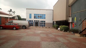 A building with a modern facade, a covered entrance, and a paved courtyard with parked vehicles. - Da 411 Hotel (Ibadan)