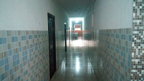 A corridor with tiled walls and a tiled floor, leading to a door at the end. - Da 411 Hotel (Ibadan)