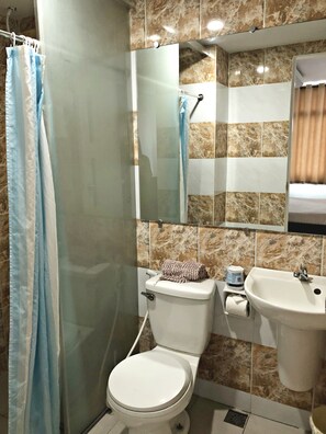 Un baño con inodoro, lavamanos, cortina de ducha y espejo.