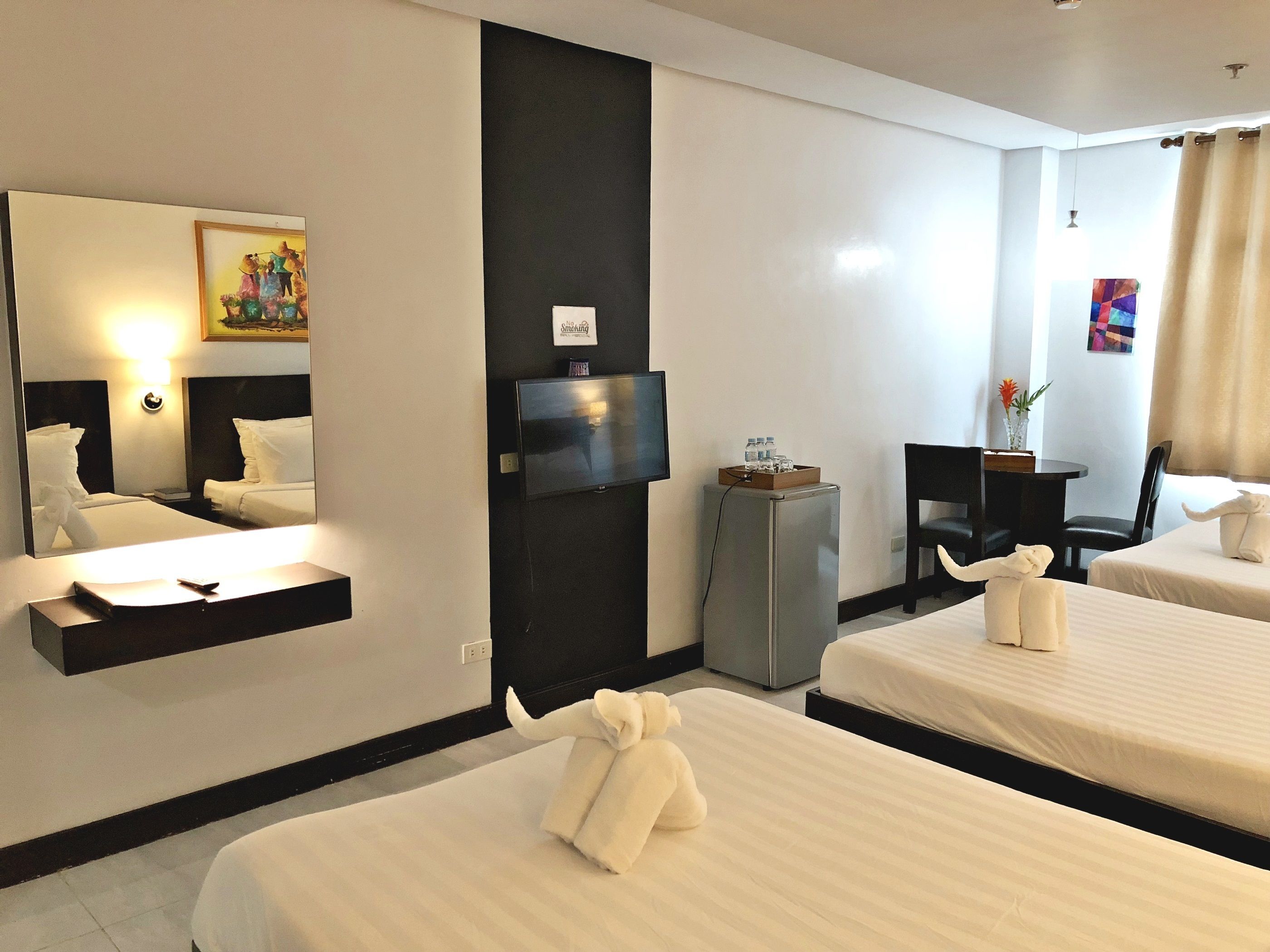 A hotel room with two beds, a TV, a minibar, and a desk with a chair.