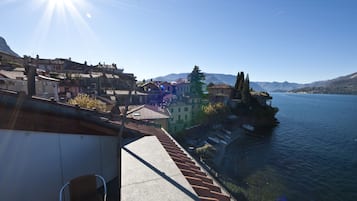 Eine Küstenstadt mit terrassenförmig angeordneten Häusern mit Blick auf ein ruhiges Meer und Berge in der Ferne.
