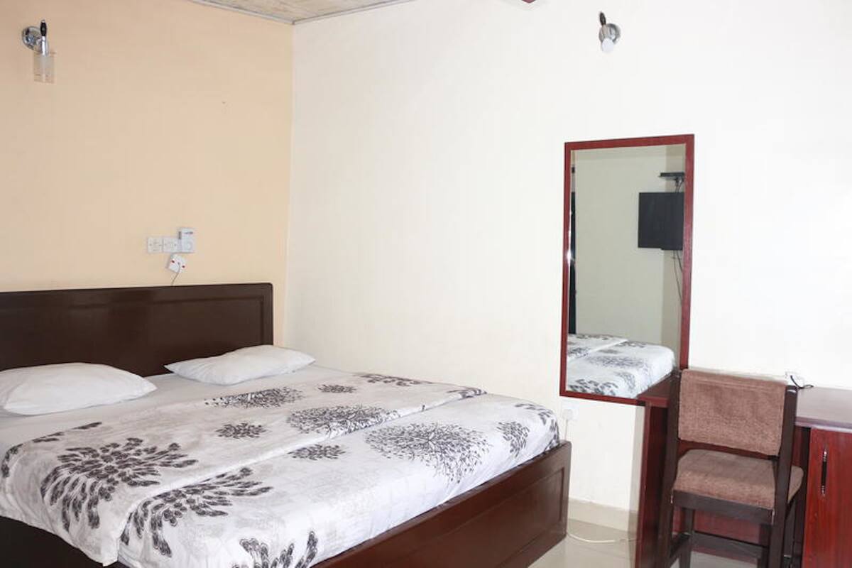Un dormitorio con una cama, una silla, un escritorio y un espejo.