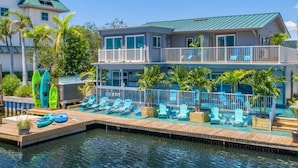 Ein Hotel am Wasser mit Poolbereich, Liegestühlen und Kajaks.