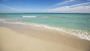 Ein Strand mit klarem türkisblauem Wasser und einem Sandufer.
