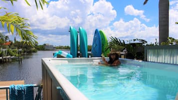 Relax by the pool, surrounded by a deck and adjacent to a serene body of water.