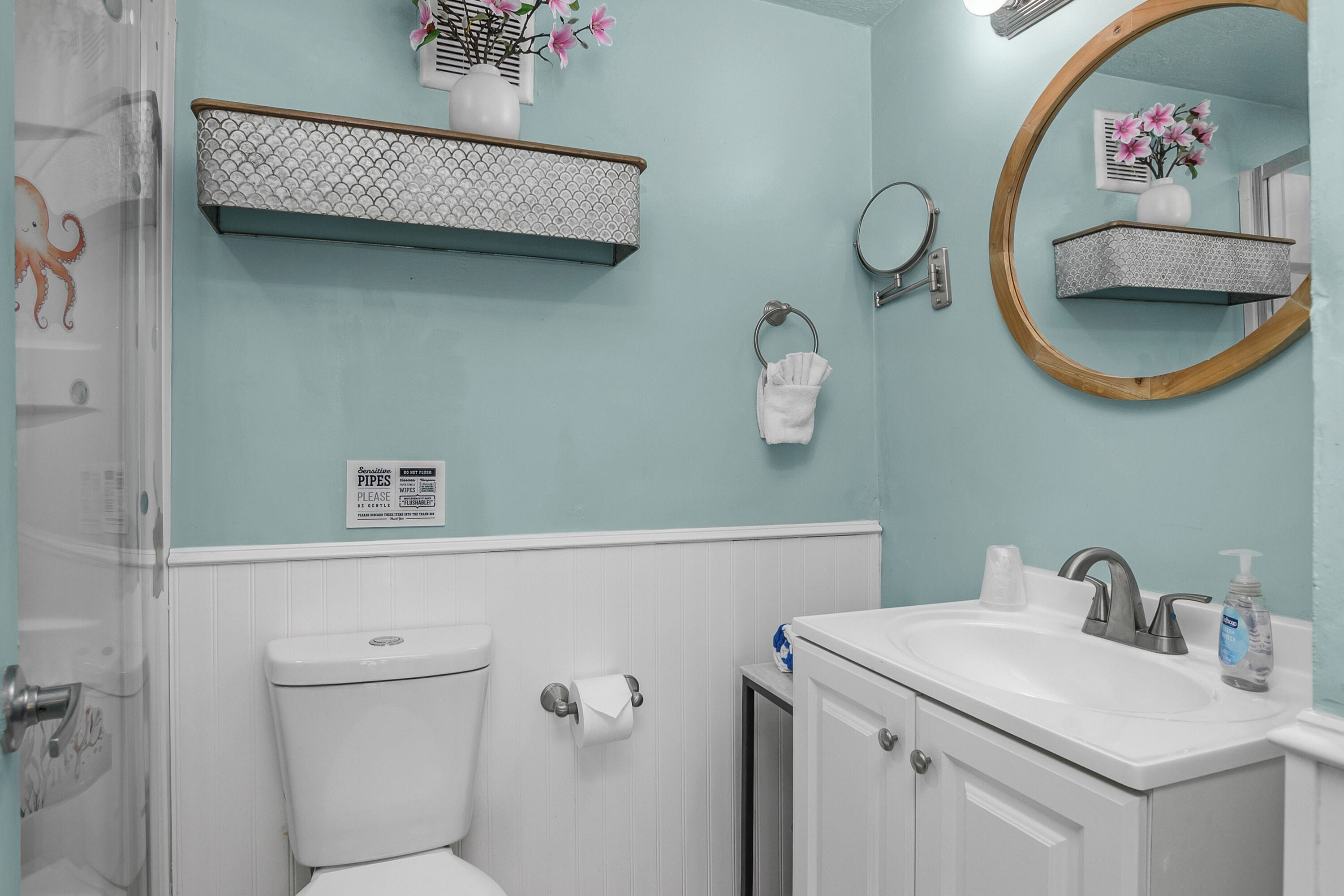 A bathroom with a toilet, sink, mirror, towel rack, and decorative shelves.