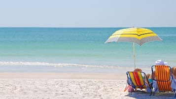 Vlak bij het strand, wit zand, ligstoelen, parasols