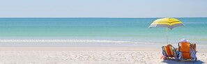 Pantai di sekitar, pasir putih, kursi berjemur, dan payung pantai