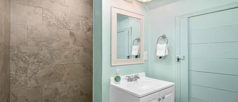 A bathroom with a white sink, a mirror, and a shower area.