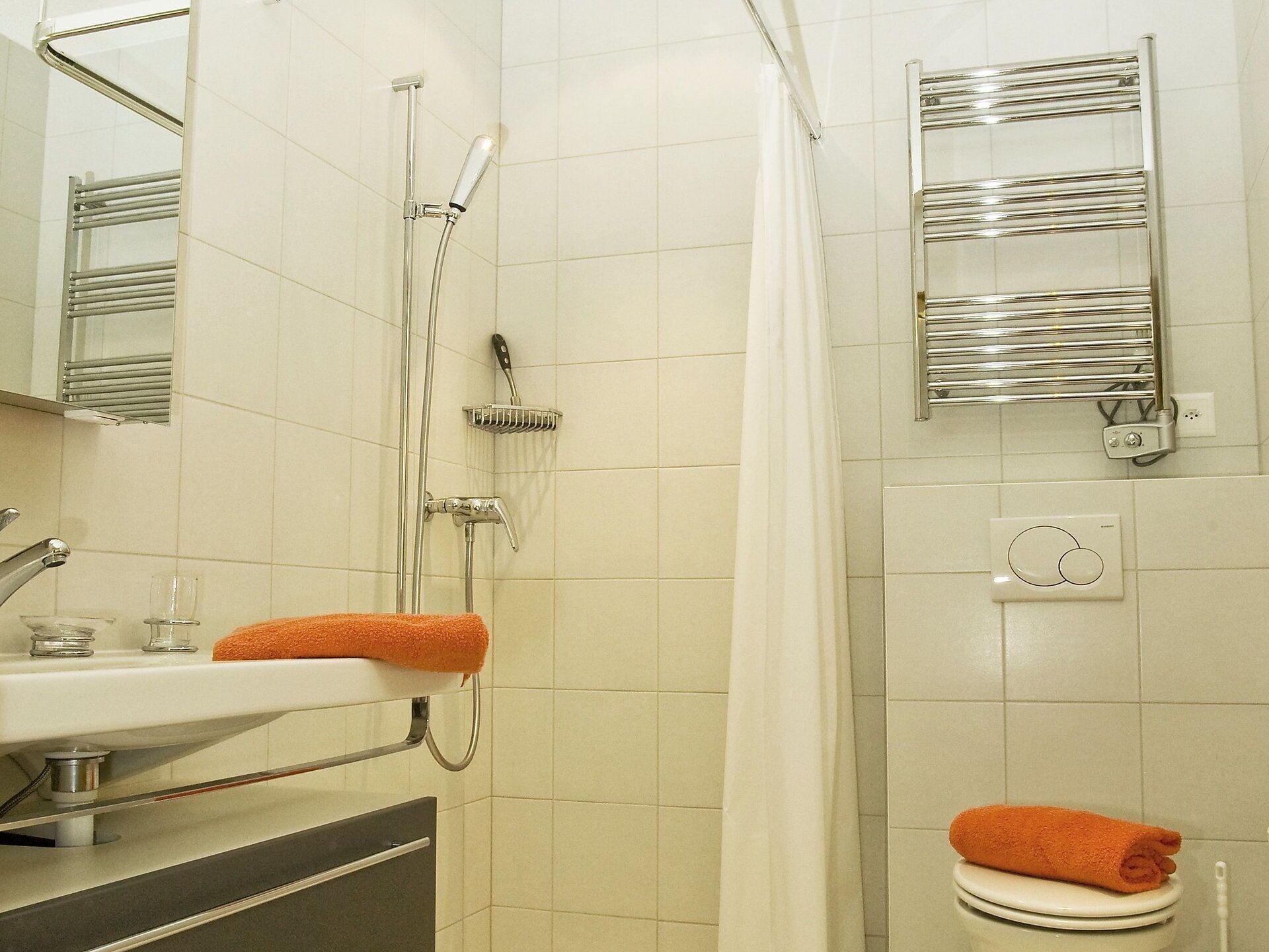 A bathroom with a shower, a sink, a toilet, and a towel rack.
