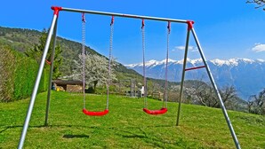A swing set in a grassy area with a mountain backdrop.