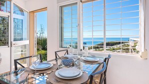 A dining table set for four with a clear view of the ocean through large windows. - Polarsol 2 (Mijas)