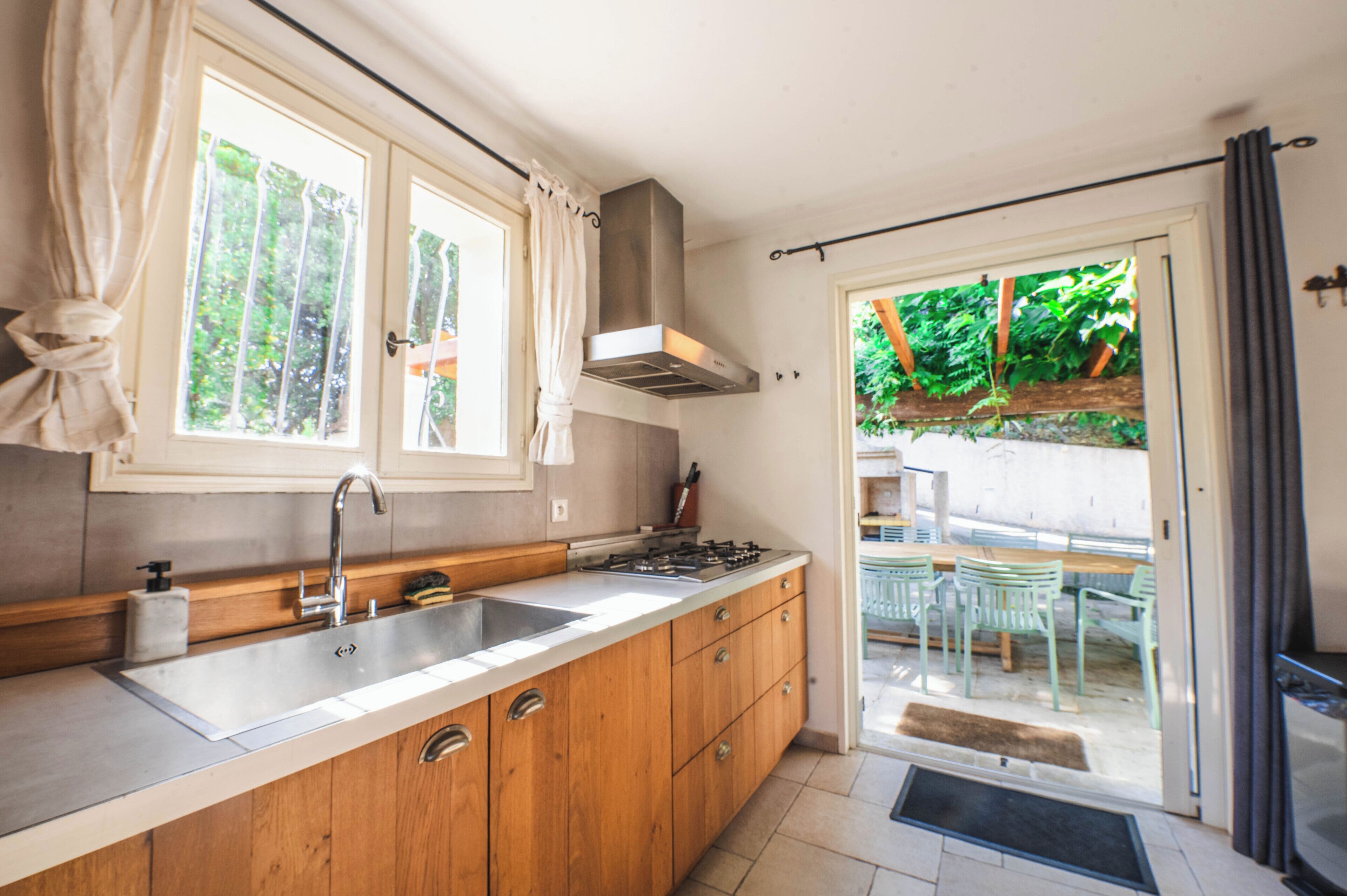Een keuken met houten kastjes, een roestvrijstalen spoelbak en een gasfornuis.