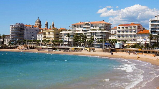 Un hôtel situé sur la côte, avec plusieurs étages, des balcons et une vue sur la plage.