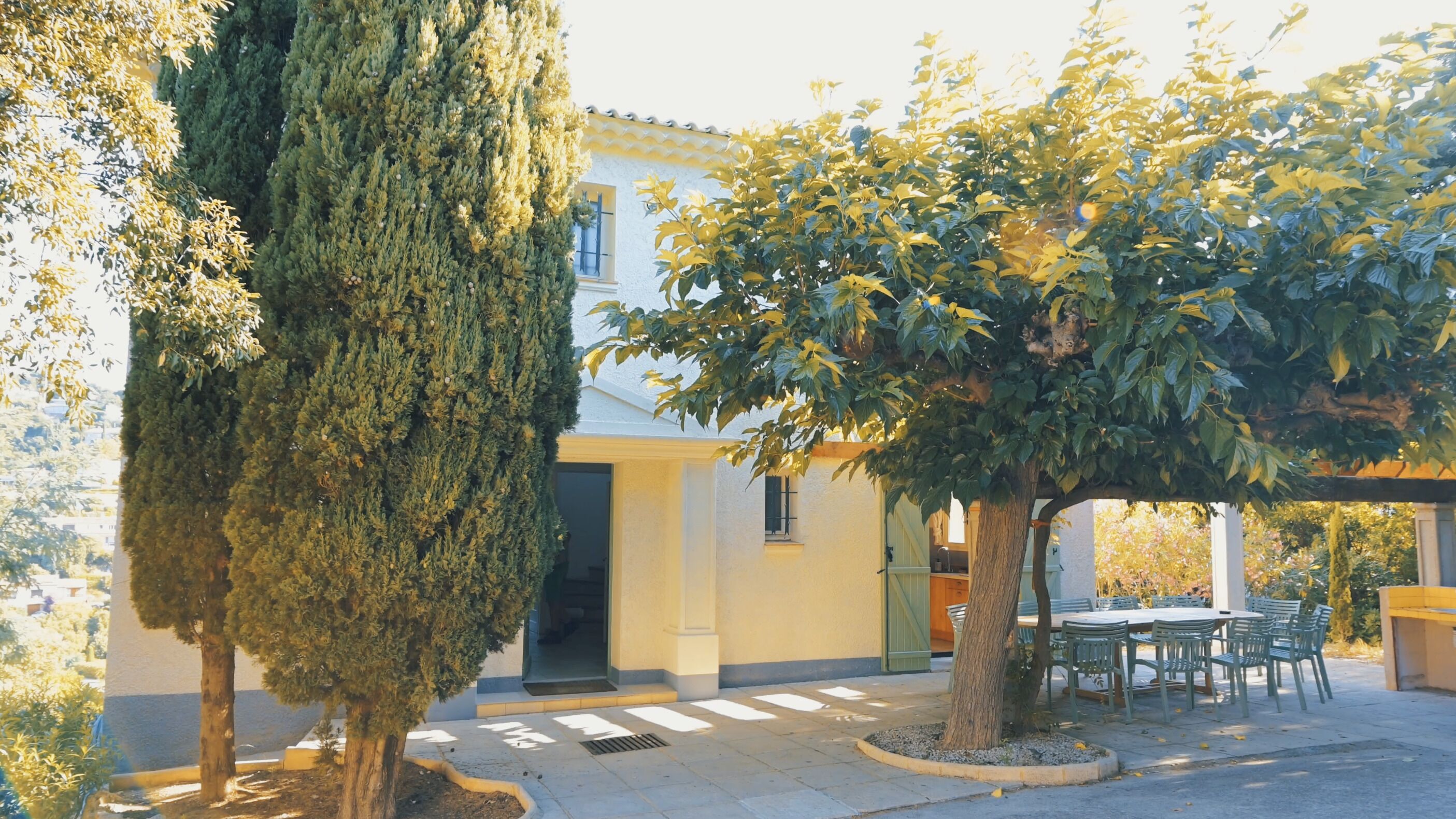 A building with a covered patio, a tall tree, and a smaller tree.