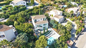Vue aérienne d’un quartier résidentiel avec une maison à deux étages dotée d’un balcon, d’une piscine et entourée de verdure.