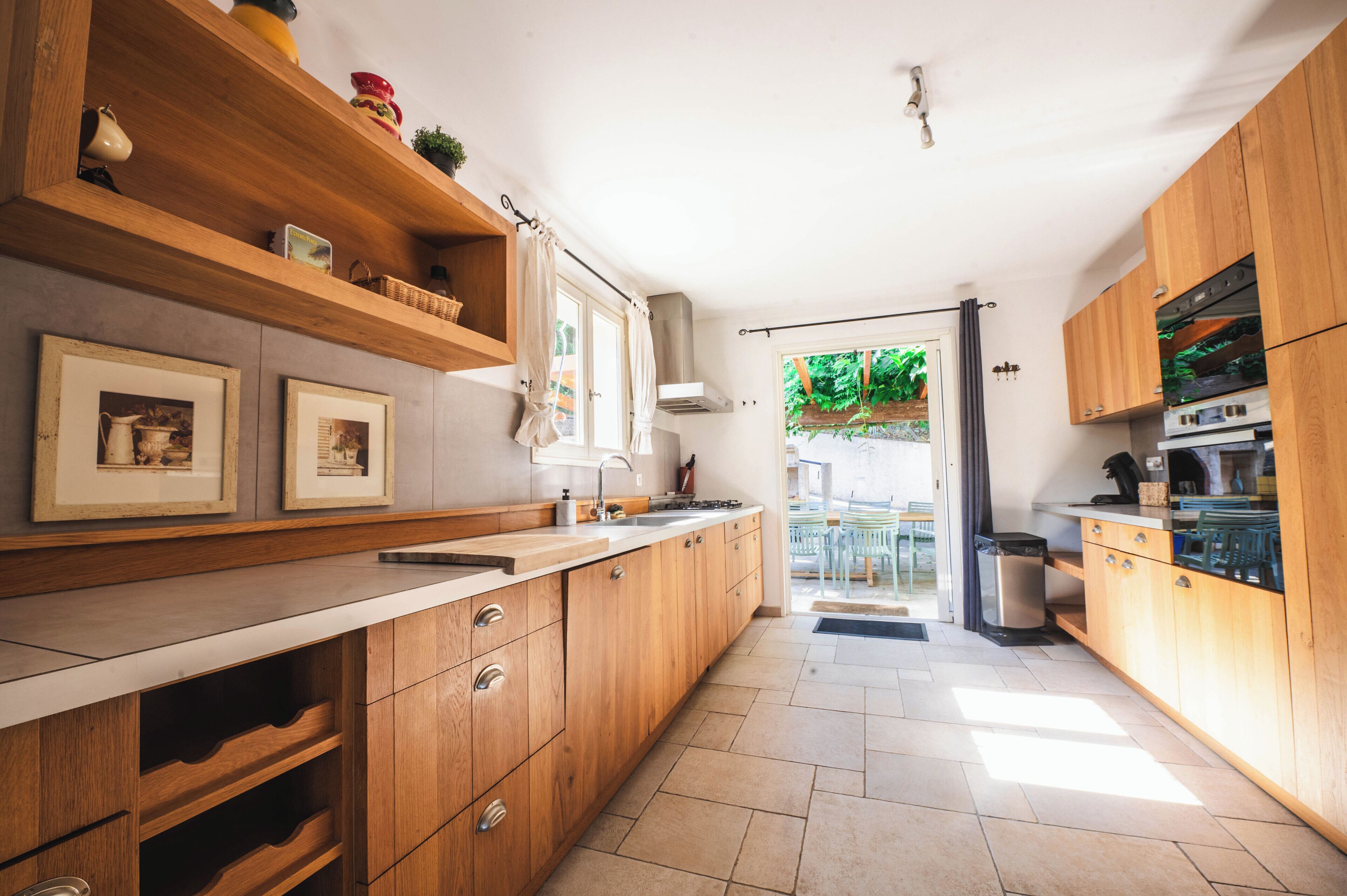 A modern kitchen with wooden cabinets, a countertop, and a view of the outdoors.