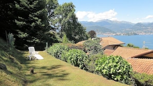 A hillside property with a lawn, a chair, and a view of a lake and mountains. - Thommy apartment in Stresa with  lake view (Stresa)