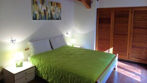 A bedroom with a bed, nightstands, a lamp, a painting on the wall, and wooden shutters. - Thommy apartment in Stresa with  lake view (Stresa)