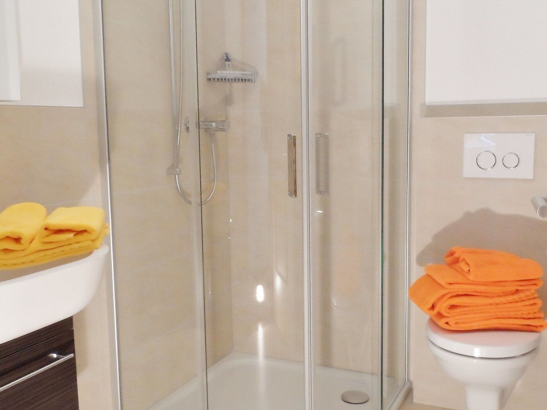 A bathroom with a glass-enclosed shower, a white sink, and a toilet.