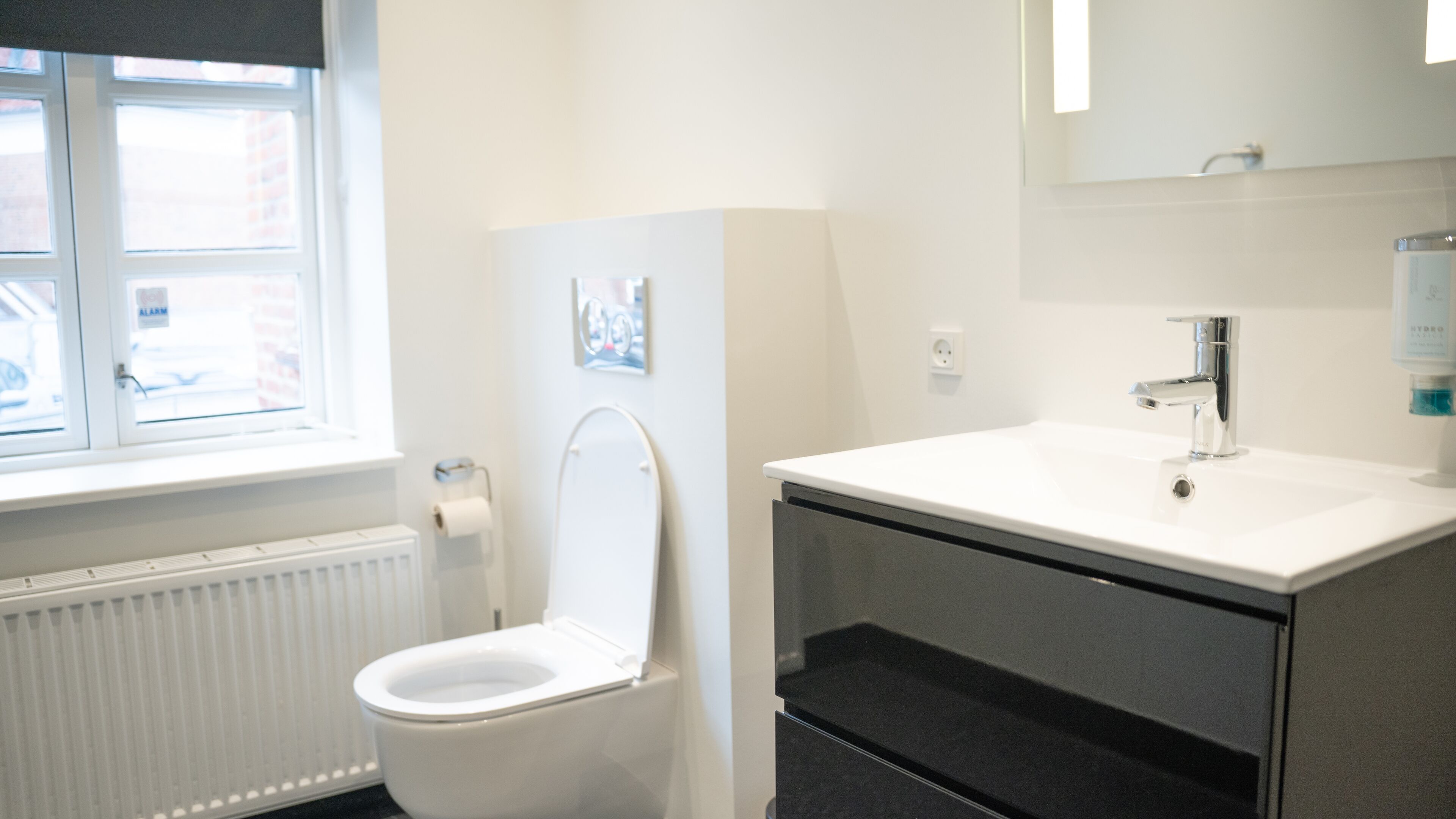 A modern bathroom with a toilet, sink, and window.