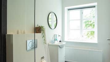 A modern bathroom with a toilet, sink, and window.