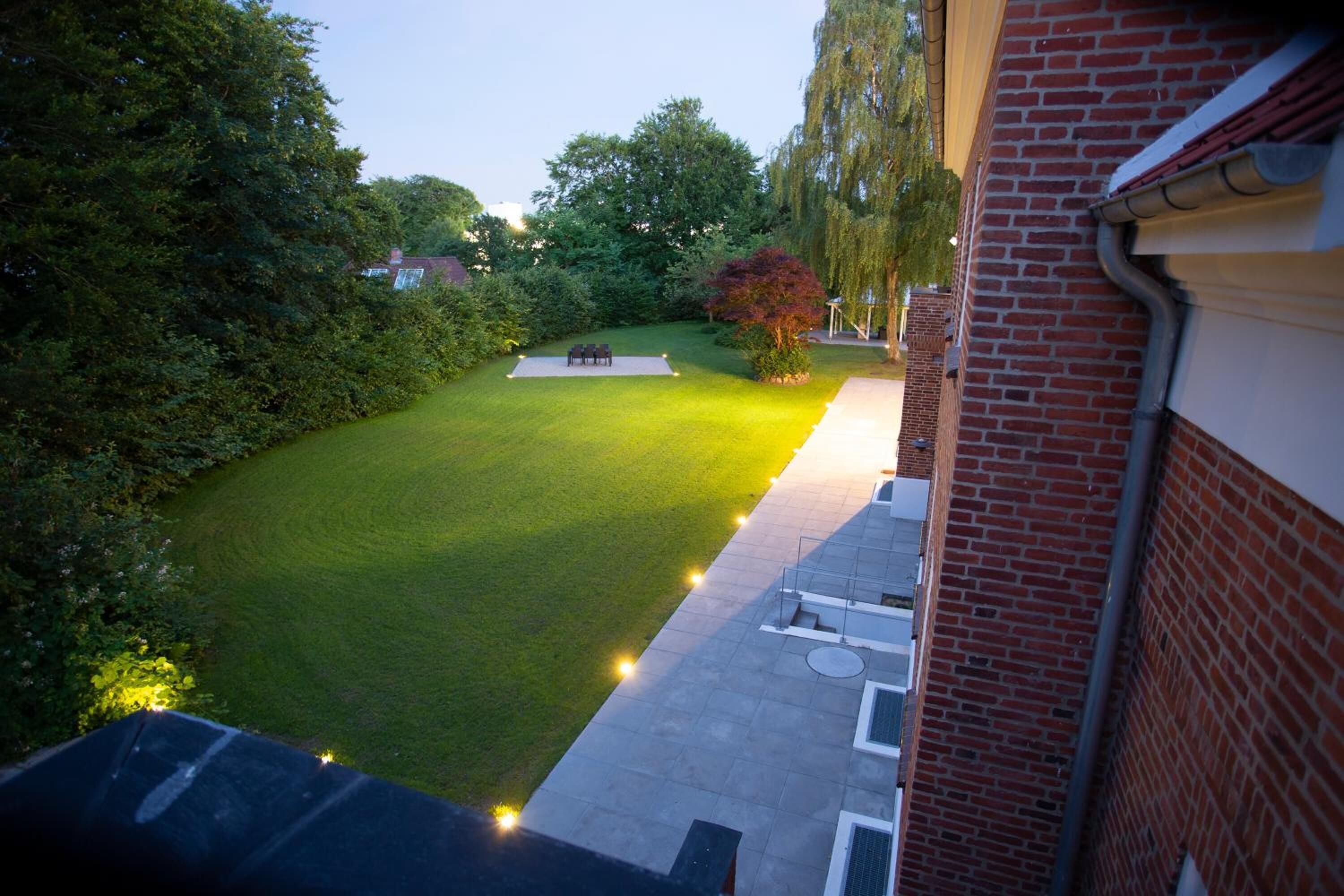 A courtyard with a lawn, a seating area, and a brick building.