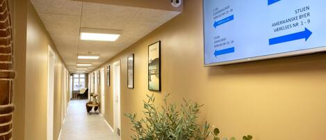 A hotel hallway with directional signs indicating room types and their locations.