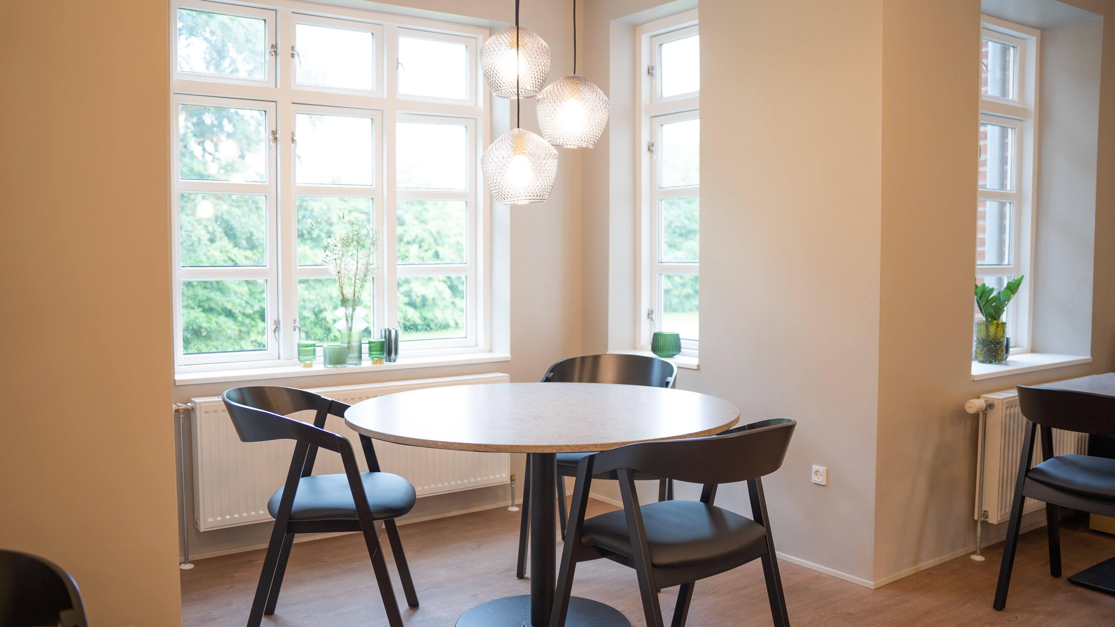 Un coin repas avec une table ronde, deux chaises et des luminaires suspendus.