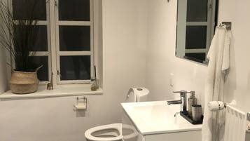 Et moderne badeværelse med toilet, vask og et vindue med en plante.