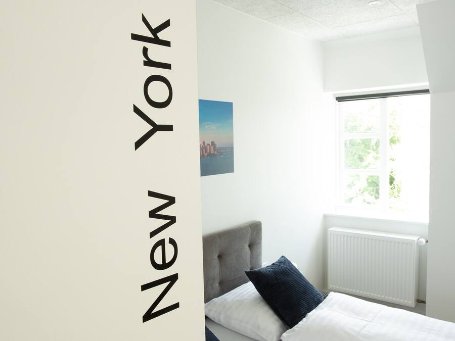 Habitación de hotel con dos camas y vista a la ciudad, con una puerta que indica '21 New York'.