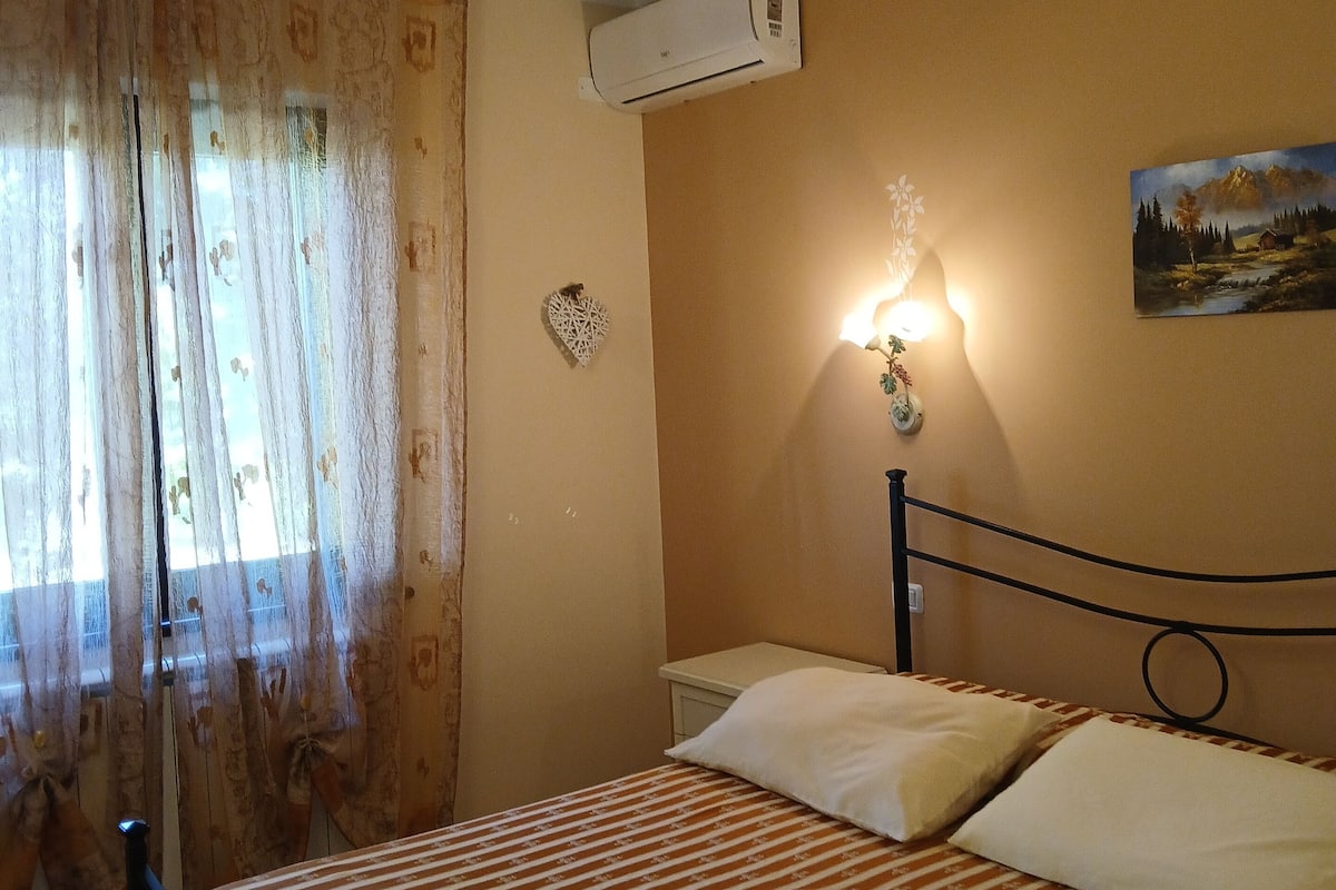 Une chambre à coucher avec un lit, un appareil de climatisation, un tableau au mur et un cœur décoratif accroché au mur.