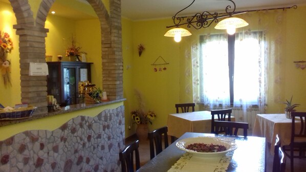Un coin repas avec un mur en pierre, un lustre et une table sur laquelle se trouve un saladier rempli de nourriture.