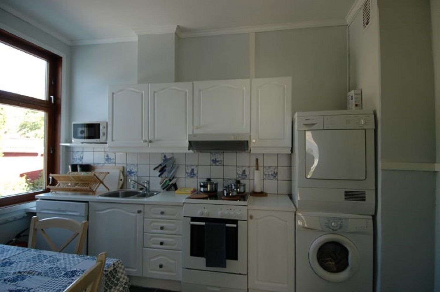 A compact kitchen with white cabinets, a microwave, a stove, and a washing machine.