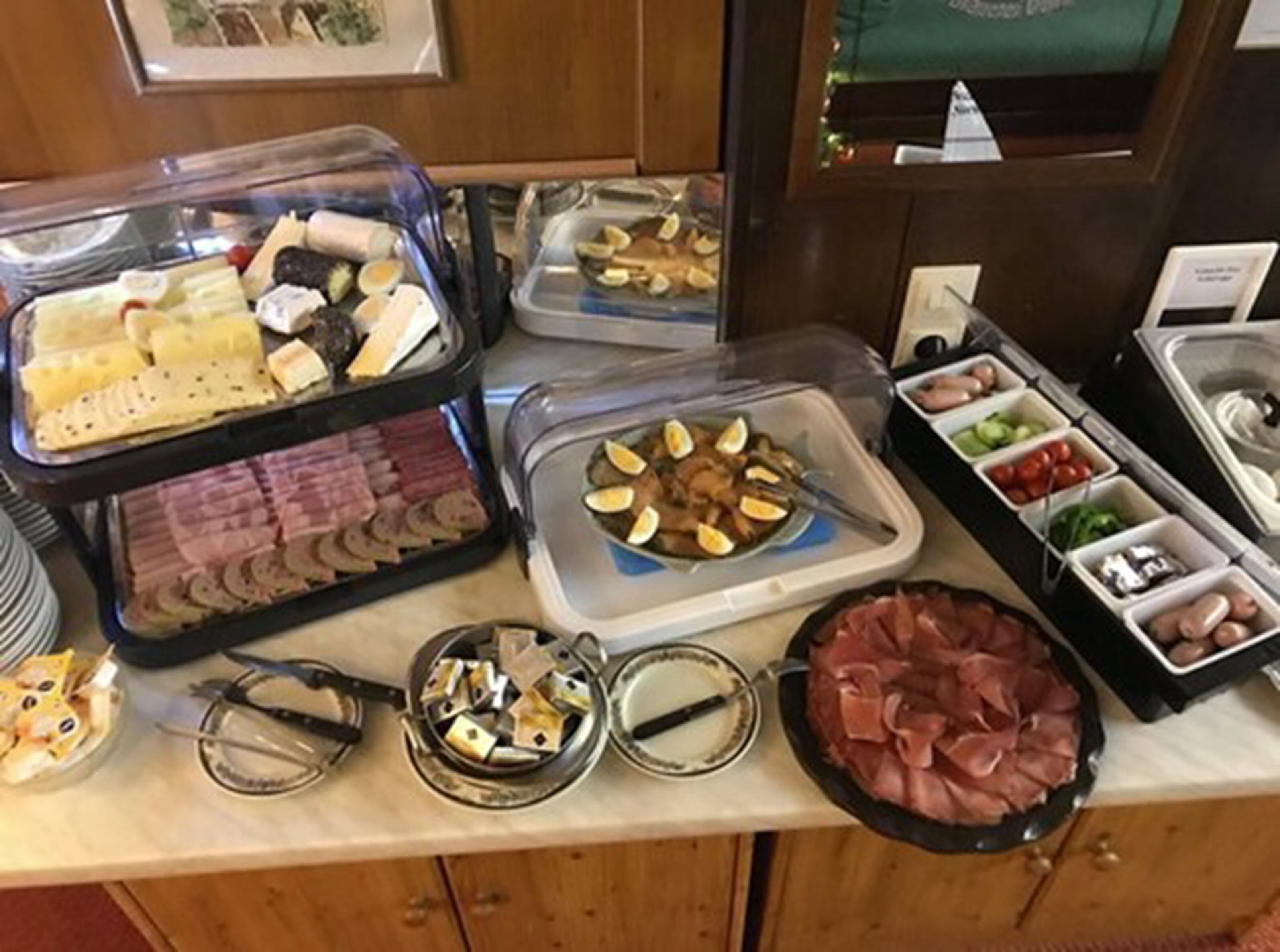 A buffet with various food items including meats, cheeses, and fruits.