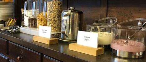 A buffet counter with various food items and a coffee pot.