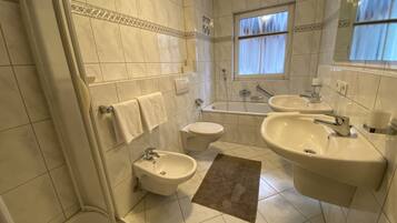 A bathroom with a bathtub, two sinks, a toilet, and a shower.