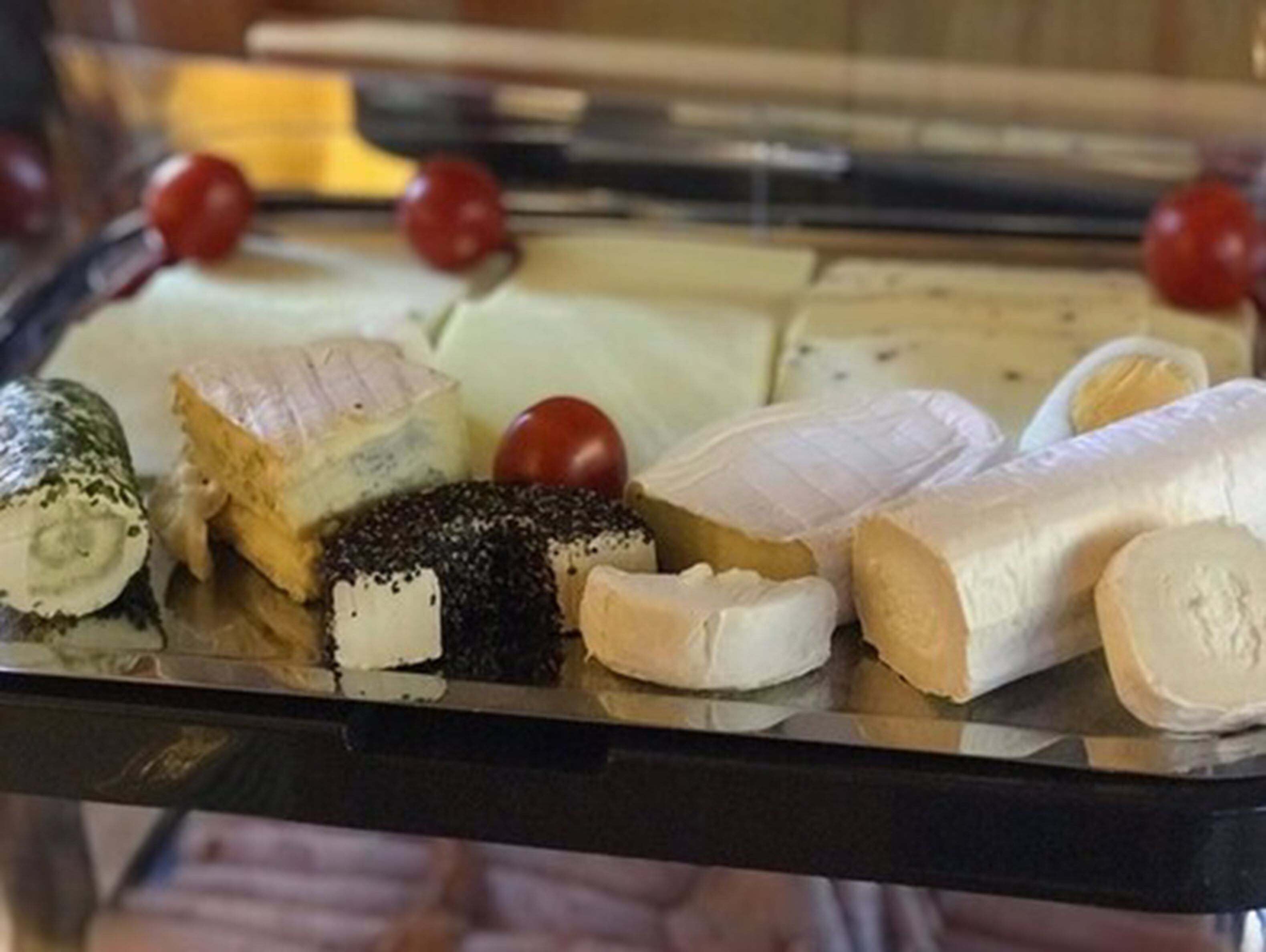 A variety of cheeses displayed in a glass case.