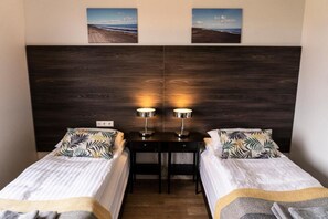 A room with two single beds, a small table, and two wall-mounted lamps. - Black Beach Guesthouse (Sveitarfélagid Ölfus)