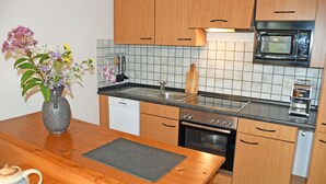 Eine kleine Küche mit Holzschränken, einer Mikrowelle, einem Backofen und einem Spülbecken.