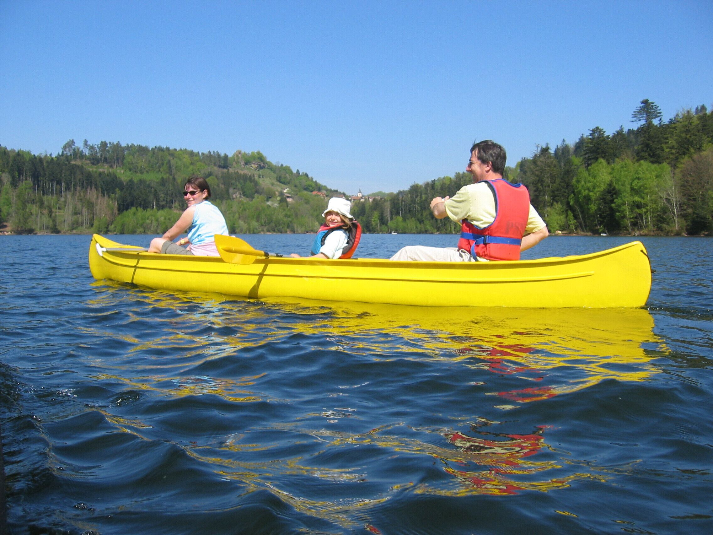 A yellow canoe on calm water with three people.
