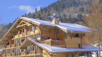 A wooden chalet with multiple balconies and a ski lift.
