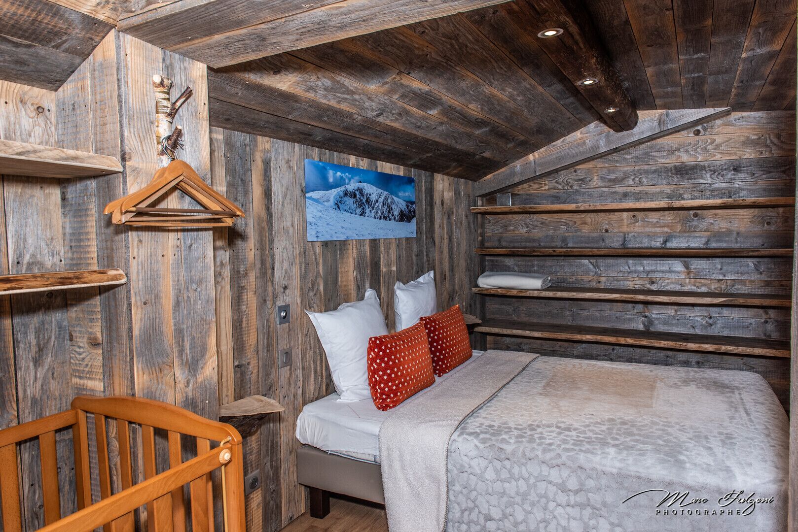 A rustic wooden room with a bed, pillows, and a wooden chair.