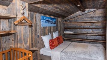 A rustic wooden room with a bed, pillows, and a wooden chair.