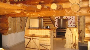 Une cuisine rustique avec des meubles en bois, un réfrigérateur, une cuisinière et un évier.